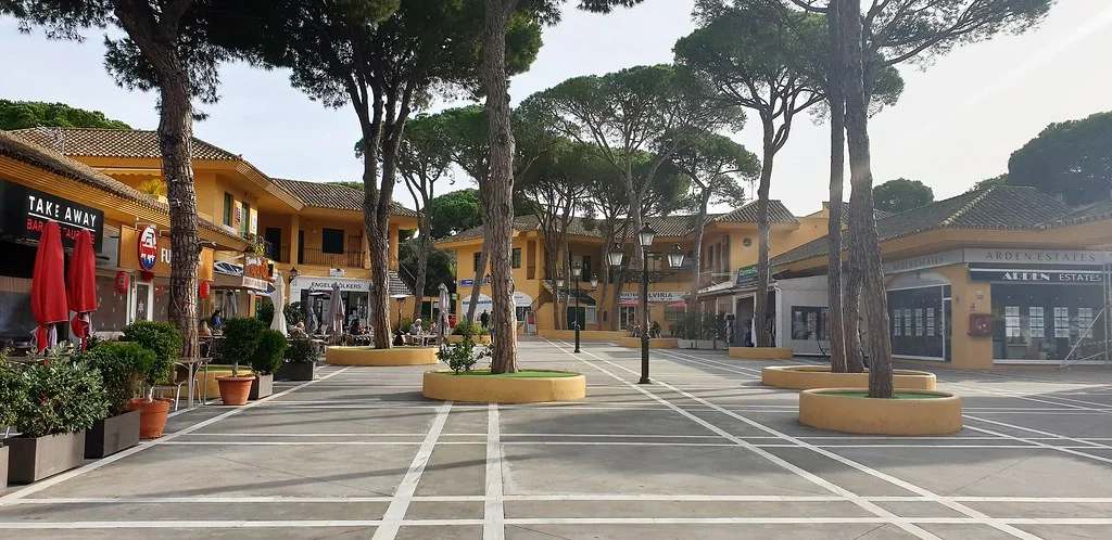 The main commercial centre in Elviria, Marbella, with shops under umbrella pines